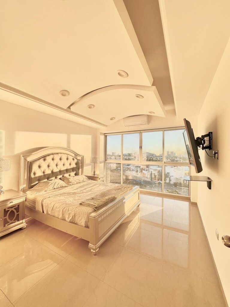Recámara principal de Penthouse con ventanales panorámicos y vista al campo de golf